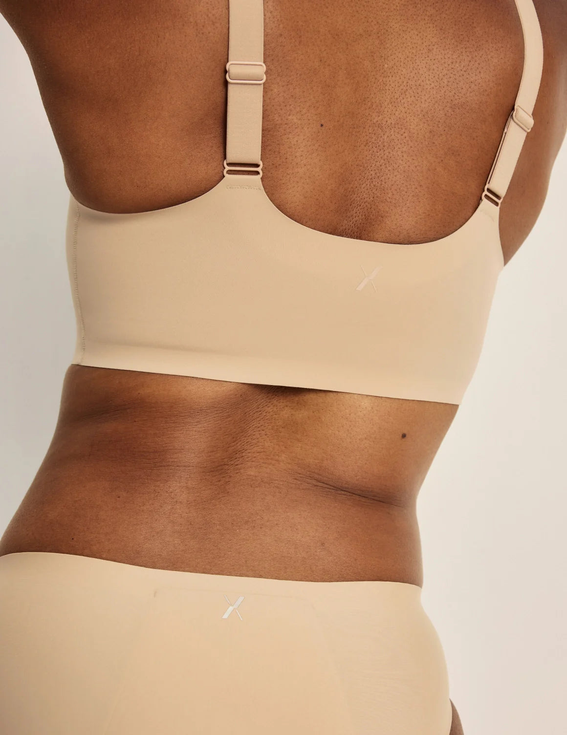 Gin is a 34DD and wearing KNIX M+ | Back view of model wearing the Revolution Adjustable Pullover Bra, highlighting the neckline, strap design, and  silhouette | Warm Sand