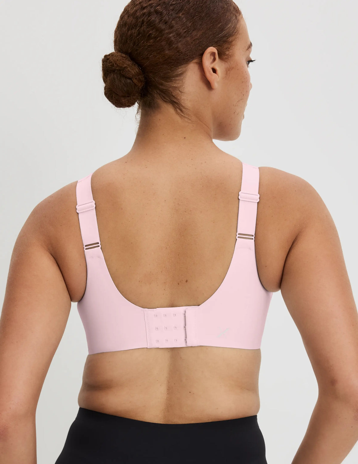 Adecia is a 34D wearing KNIX M+ | Back view of model wearing the Catalyst Sports Bra, highlighting the neckline, strap design, and smooth silhouette | Pink Party