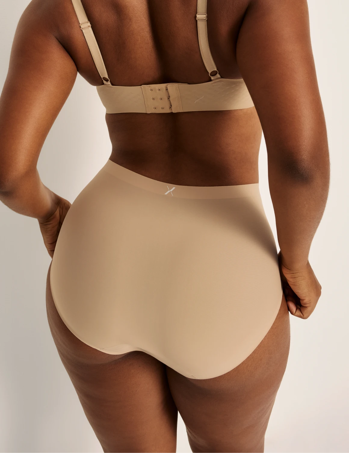 Amber has 46” hips, and wearing KNIX L | Back view of model wearing the Light Leakproof No-Show High Rise highlighting the coverage and smooth fit | Warm Sand