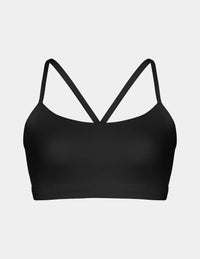 A black sports bra with thin crisscrossing straps at the back, shown against a light gray background.